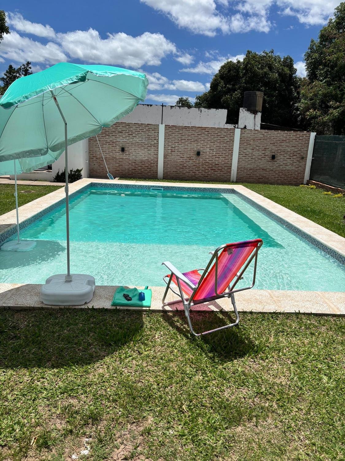 Pileta con reposera y sombrilla en un día soleado